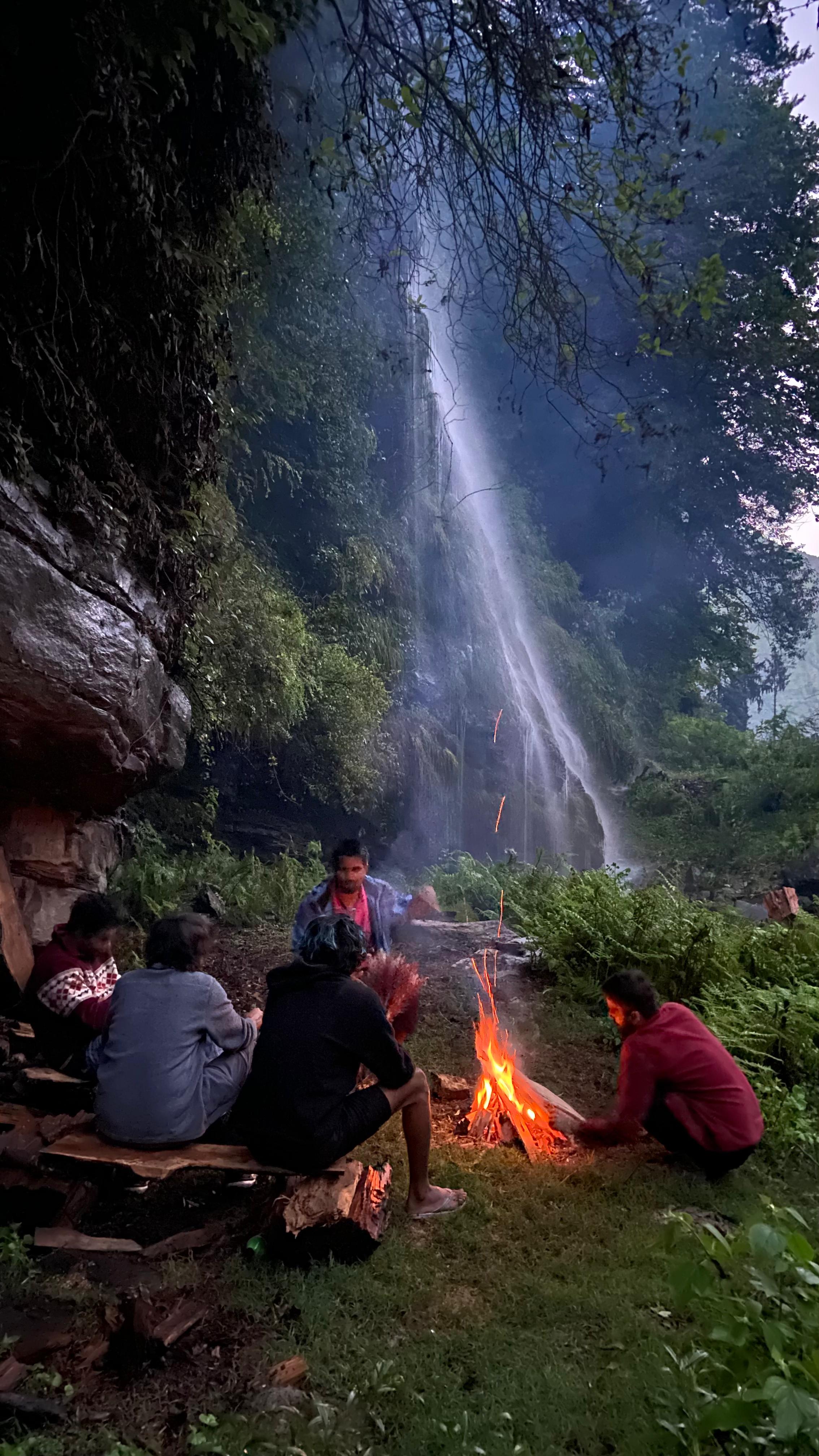 Campfire by a waterfall at dusk